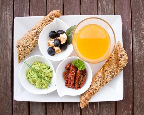 Fresh vegetables, whole grain bread and a bowl of warm soup on a rustic table
