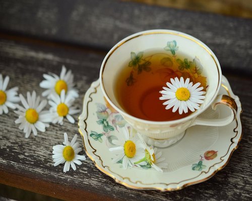 A cup of herbal tea next to an open notebook on a cozy wooden desk